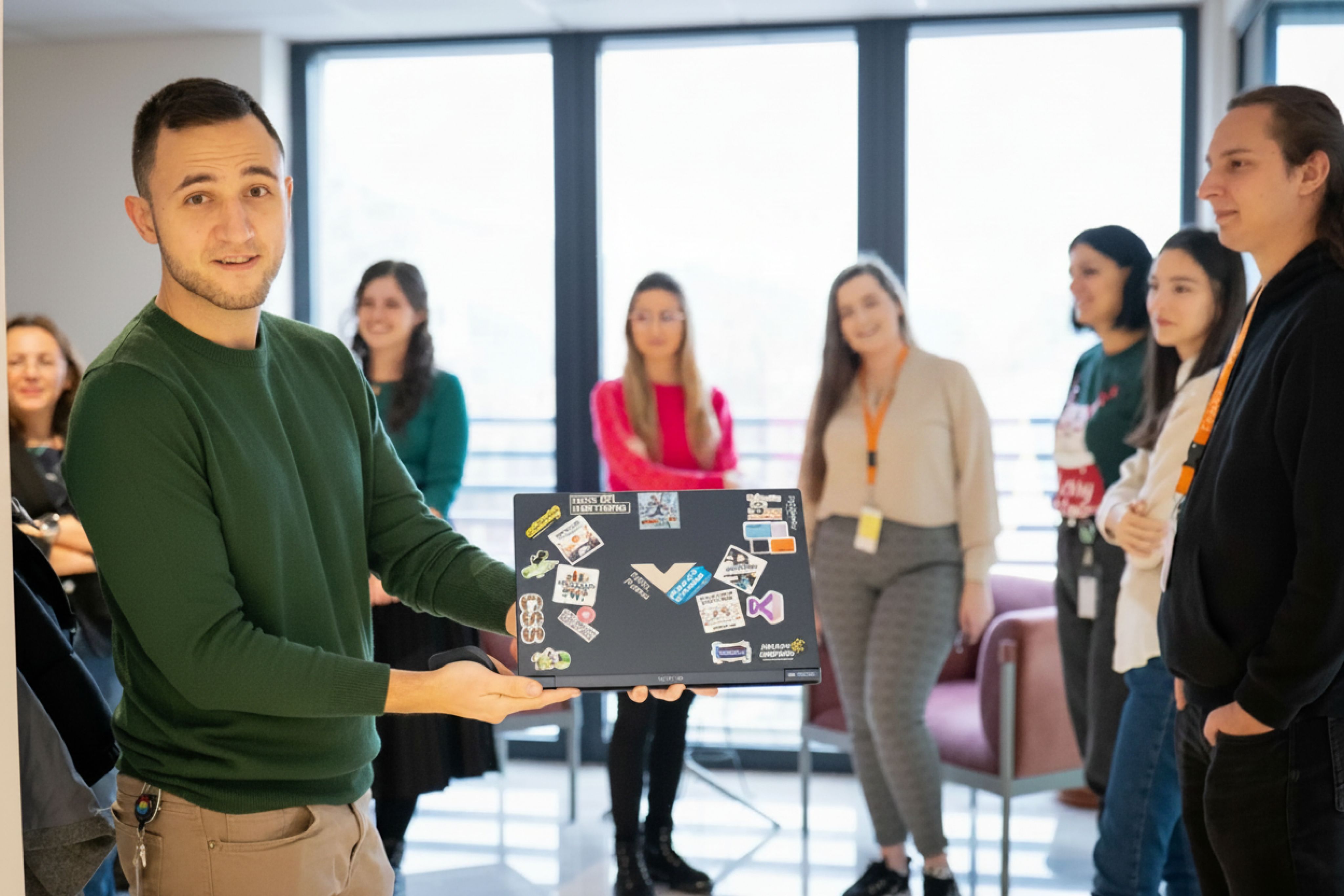 Engineer presenting a sticker-covered laptop to colleagues