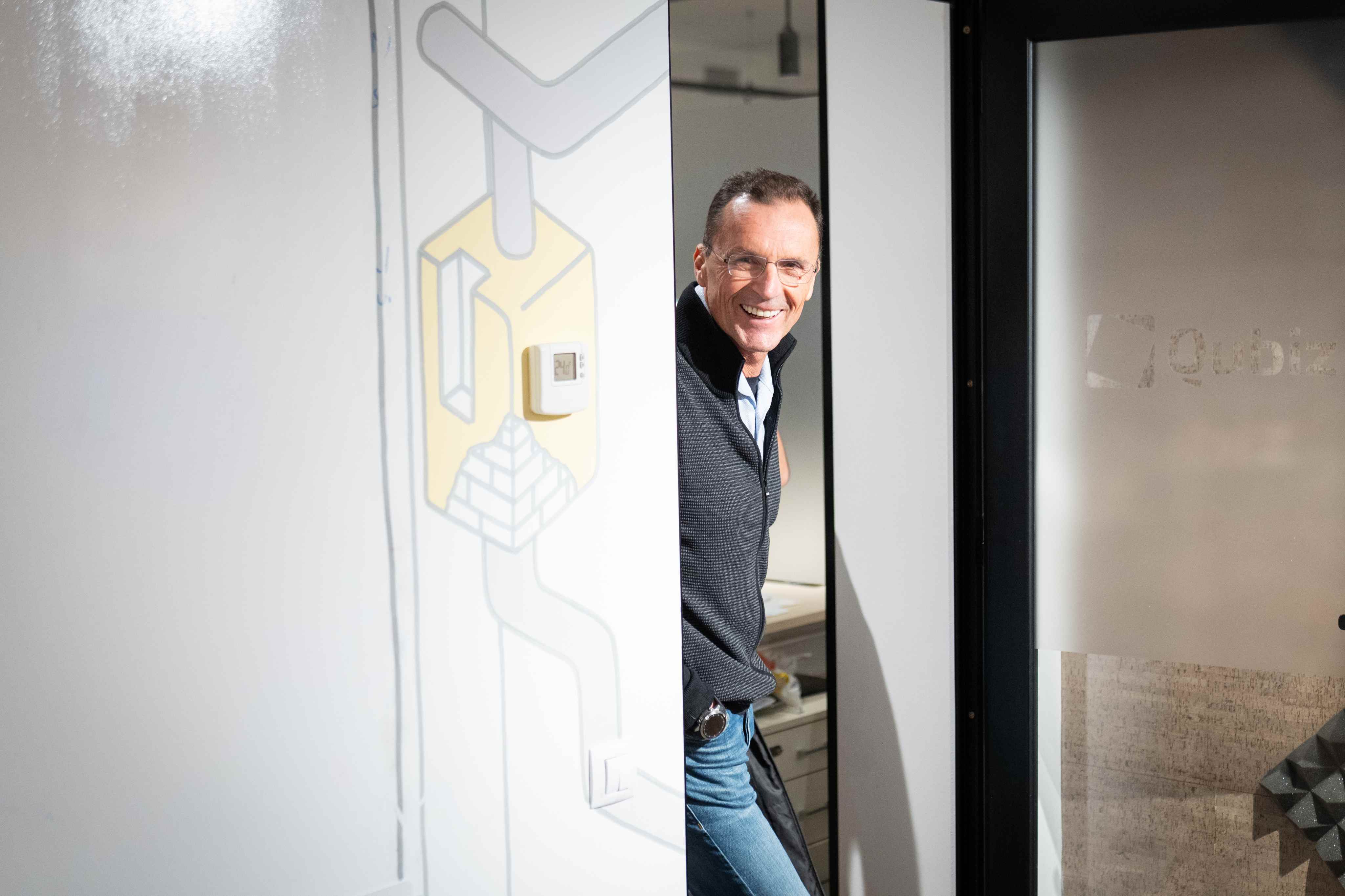 Colleague smiling around a glass office door at the Qubiz studio